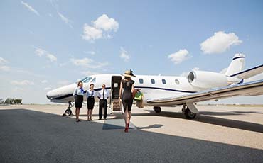 Rich Woman Walking Towards Private Jet At Airport Terminal